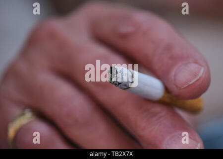 Macro photo d'une vieille femme main tenant une cigarette courte, se concentrer sur le dessus de la main, la cigarette est flou Banque D'Images