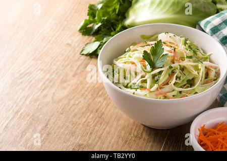 Salade de chou blanc dans un bol et les ingrédients sur la table en bois Banque D'Images