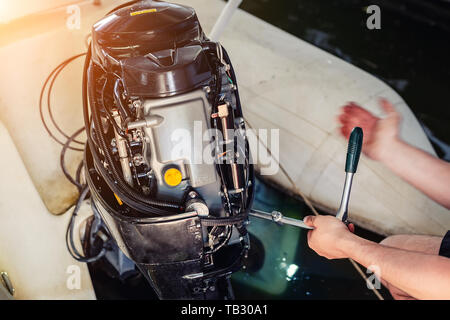 mécanicien réparant le moteur de bateau gonflable au garage du bateau. Service et entretien saisonniers des moteurs d'expédition. Moteur du réservoir avec couvercle ouvert Banque D'Images