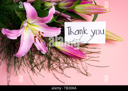 Merci remarque avec Lily fleurs bouquet sur fond rose Banque D'Images