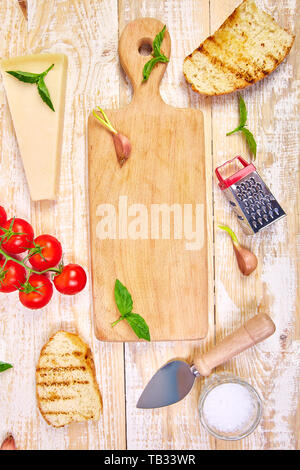 Ingrédients alimentaires italiens, avec tomates, basilic, parmesan, huile d'olive, ail, pain, sur fond de bois pour la cuisson. Vue de dessus, vue de ab Banque D'Images