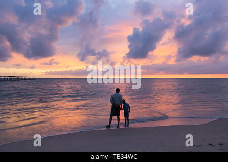 Père et fils en regardant le coucher du soleil spectaculaire à Alleppey Alappuzha Beach au Kerala Inde Banque D'Images