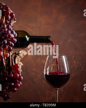 Verseur à vin rouge d'une bouteille dans un verre. Image conceptuelle sur le thème de la vinification. Copie de l'espace pour votre texte. Banque D'Images