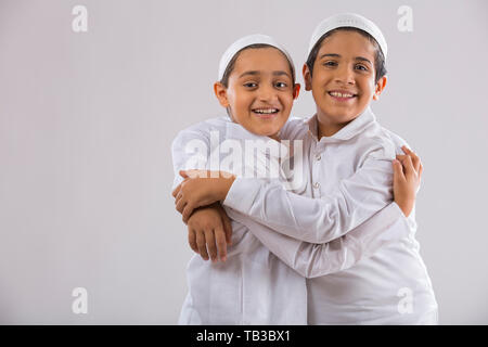 Les jeunes garçons musulmans, avec des plafonds de l'autre côté hugging Banque D'Images