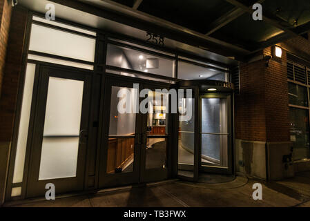 La ville de New York, USA - 31 juillet 2018 : Entrée d'un immeuble avec une porte tournante de nuit à Harlem, Manhattan, New York City, USA Banque D'Images