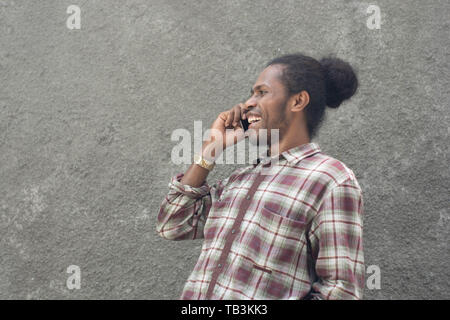 Jeune homme noir barbu en tenue décontractée using smartphone Banque D'Images
