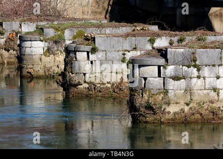 Vieux pont détruit et pylône de pierre roche foundation partiellement recouverts de terre et de mousse entourée de la rivière claire sur le printemps chaud et ensoleillé Banque D'Images