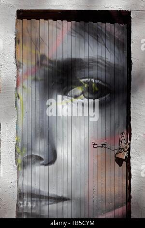 Triste visage de femme, peint sur une porte, graffito, art de rue dans le quartier de Carme, vieille ville, Valencia, Espagne Banque D'Images