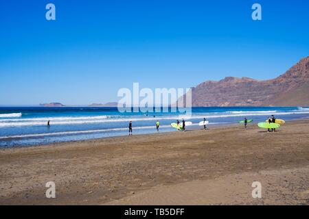 Surfer avec une planche de surf sur la plage, Playa de Famara, Caleta de Famara, Lanzarote, îles Canaries, Espagne Banque D'Images