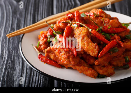 Sauté de poulet Szechuan en sauce épicée à l'ail, oignon et piment close-up sur une plaque sur la table horizontale. Banque D'Images