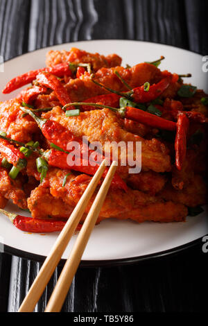 Szechuan poulet épicé avec du piment, des oignons dans une sauce épicée sur une plaque verticale sur la table. Banque D'Images