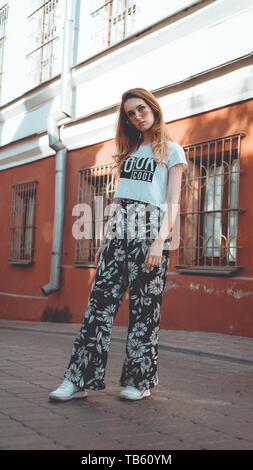 Fashion portrait jolie femme élégante en posant des lunettes dans la ville, la rue de la mode. Vous avez l'air cool sur t-shirt blanc Banque D'Images