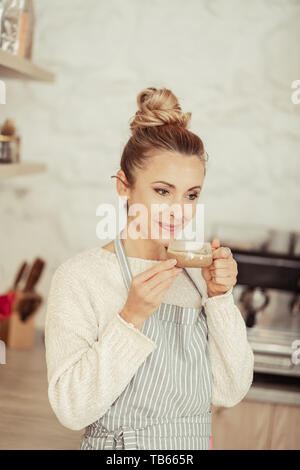 La rêverie. Belle thoughtful woman smiling and holding sa tasse de café. Banque D'Images