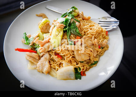 Nouilles instantanées poulet sauté piment et feuille de basilic sur plaque blanche vue de dessus - le style Thai Noodle alimentaire Banque D'Images