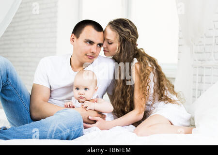 Mère et père avec un petit bébé dans un lit Banque D'Images