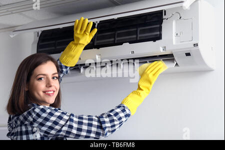 Young woman cleaning air conditionné à la maison Banque D'Images