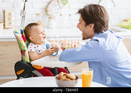 Famille amour concept. Papa jouant avec son bébé adorable fils dans la cuisine, rire ensemble, l'espace vide Banque D'Images