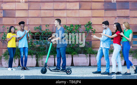 Hipster homme conduisant scooter électrique dans la ville de plein air Banque D'Images