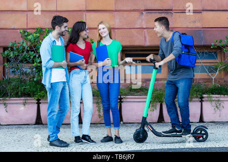 Hipster avec étudiants et amis scooter électrique dans la ville de plein air Banque D'Images