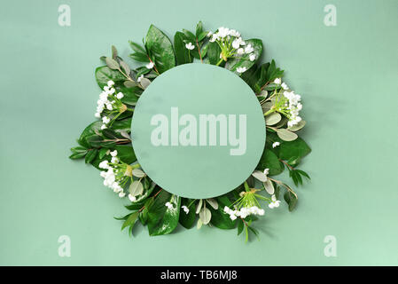 Mise en page créative faite de feuilles tropicales et des fleurs blanches sur fond vert. Vue d'en haut. Mise à plat. L'été ou printemps nature concept. Vide pour publicité Banque D'Images