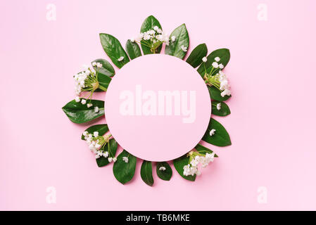 Mise en page créative faite de feuilles tropicales vert et de fleurs blanches sur fond rose. Vue d'en haut. Mise à plat. L'été ou printemps nature concept. Cache pour l'adv Banque D'Images