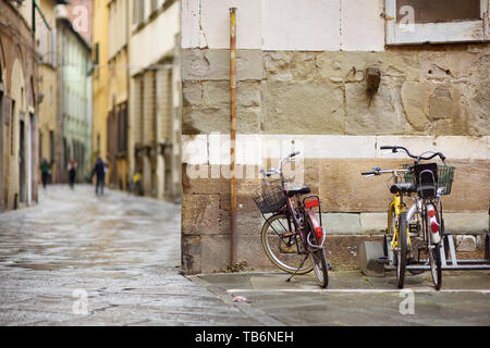 Les vélos garés sur les belles rues médiévales de Lucques, ville connue pour sa ville de l'époque Renaissance intacts les murs, Toscane, Italie. Banque D'Images