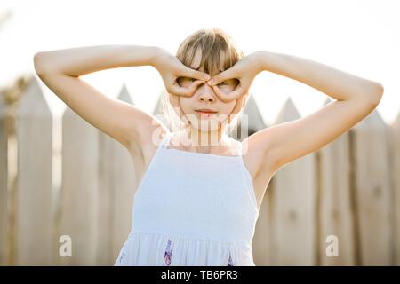 Jeune fille en robe blanche pilote volant à l'aide de faux semblant et lunettes casque vintage Banque D'Images