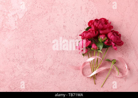 Bouquet de belles pivoines et ruban rose sur un fond de couleur, de l'espace pour le texte Banque D'Images