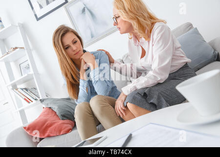 Femme d'âge moyen psychologyst traitement par client à la séance du bureau de toucher l'épaule du patient soutenir conversation Banque D'Images