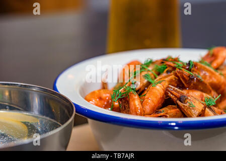 Les crevettes préparées avec de l'aneth dans un bol sur la table avec deux verres de bière et de l'eau Banque D'Images