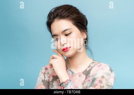 Portrait d'une belle fille de l'Asie en étant debout sur fond bleu Banque D'Images