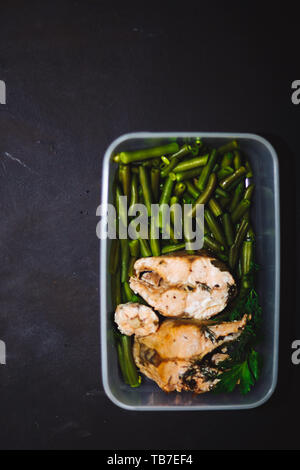 Collation santé, de l'alimentation dans un récipient. Poisson rouge cuit, saumon rose, saumon et haricots verts sur fond noir close up. Vue de dessus, copiez l'espace. des fo Banque D'Images
