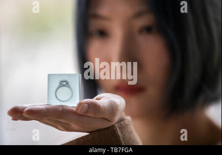 Étudiant en design de bijoux Zhan Shi examine de plus près sa pièce intitulée Le Gin sur la glace qui dispose d'une bague Tiffany situé dans un cube de verre à l'aperçu du média de l'Edinburgh College of Art degré montrent à Édimbourg. Banque D'Images