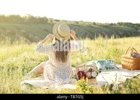 Femme heureuse vie, belle fille détendue dans un chapeau de paille sur la nature de l'arrière sur pique-nique - camping. Banque D'Images