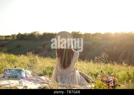 Femme heureuse vie, belle fille détendue dans un chapeau de paille sur la nature de l'arrière sur pique-nique - camping. Banque D'Images