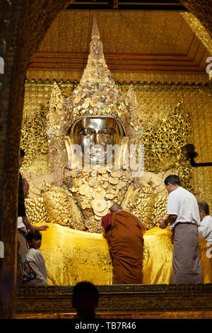 MANDALAY, MYANMAR - le 25 janvier : un moine aident à couvrir les jambes de l'image du Bouddha d'or à la fin de la journée au temple, Mandalay Mahamuni paya le 25 J Banque D'Images