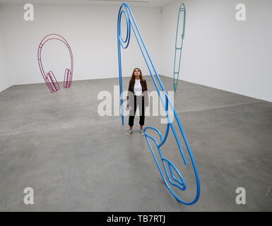 Une galerie à l'employé regarde 'Safety Pin' par Michael Craig-Martin, parmi ses autres œuvres 'casque' (gauche) et 'Fountain pen' (à droite) à l'ouverture de sa nouvelle exposition de sculpture, à la Gagosian, au centre de Londres. Banque D'Images