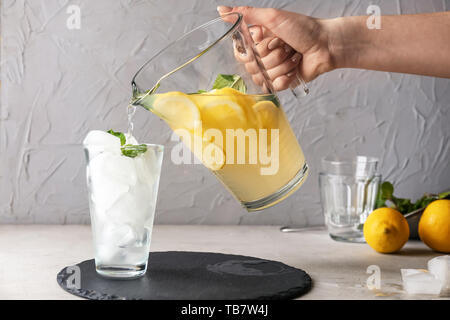 Woman pouring limonade fraîche dans un verre sur la table Banque D'Images