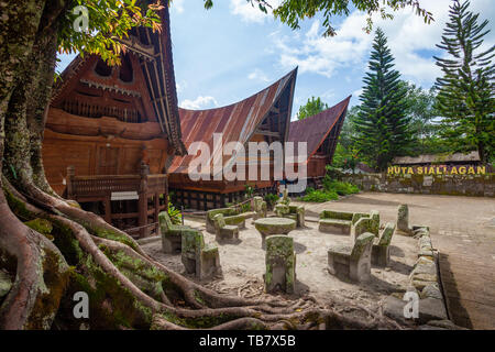 Chaises en pierre d'Ambarita et traditionnelles maisons toit Batak, île Samosir, Lac Toba Banque D'Images