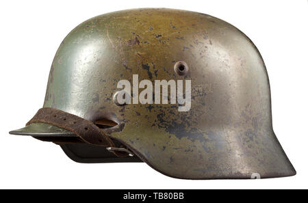 Un casque d'acier M 35 avec de la peinture de camouflage, le crâne gravé sur l'intérieur de 'E64' (Suisse saxonne) Emaillierwerke, petites perforations sur le côté gauche causée par une coquille splinter. Multi-couleur camouflage appliqué sur l'original de la peinture gris-Luftwaffe, les vestiges des deux emblèmes visible sous le camouflage. Complet avec revêtement intérieur et jugulaire historique., historique du 20e siècle, Editorial-Use-seulement Banque D'Images