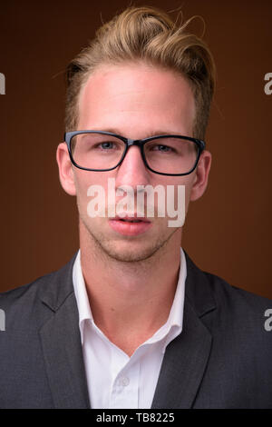 Studio shot of young handsome businessman contre fond brun Banque D'Images