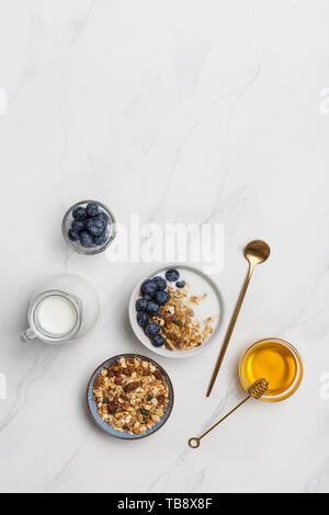 Copie espace porridge avec de l'avoine, le lait, les bleuets et le miel sur fond blanc. Ingrédients pour un petit-déjeuner sain. Espace libre pour le texte Banque D'Images