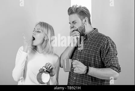 Trop tôt l'éveil. Dormir Couple pas assez de temps. Boire le café du matin le bâillement de la famille est confrontée. Réveil matinal par la haine. Habitude nuisible à dormir trop longtemps. Éveil oversleep Couple tenir réveil. Banque D'Images