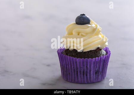 Cupcake en violet pack décoré de marbre blanc sur les bleuets Banque D'Images