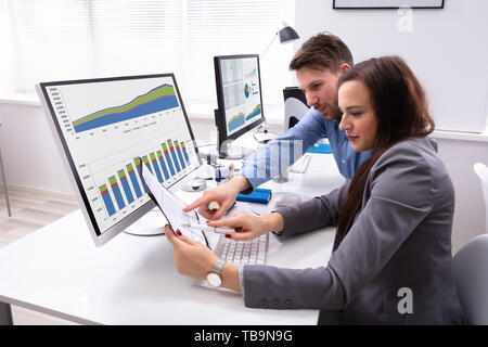 Deux Smiling couple sur le document tout en travaillant au bureau Banque D'Images