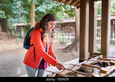 Tokyo, Japon Meiji Shrine fontaine de purification de l'eau entrée d'affaires femme fille au printemps personne plaçant louche Banque D'Images