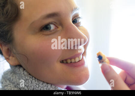 Gros plan du visage jeune femme heureuse de manger des aliments de collation craquelins de riz japonais sur voyage en avion à Tokyo, au Japon avec le fond de la fenêtre Banque D'Images