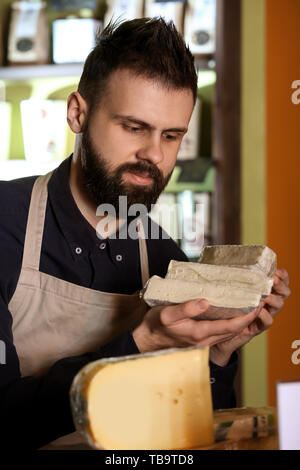 Vendeur mâle avec fromage délicieux en magasin Banque D'Images