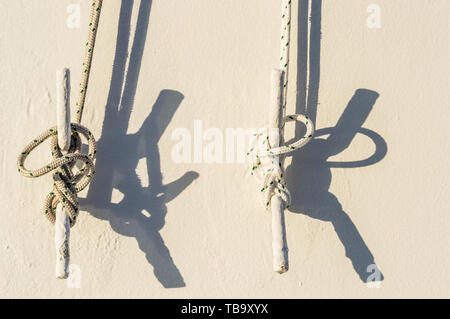 Deux milles marins des cordes attachées avec noeuds marins à crampons de métal blanc sur un mur extérieur d'une croisière dans la lumière du soleil du matin. Banque D'Images