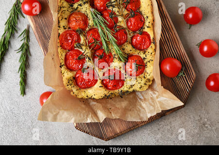 Planche de bois avec de la focaccia italienne savoureuse sur table gris Banque D'Images